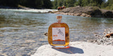Eine Flasche WUYD Single Malt Whisky steht auf einem Stein, im Hintergrund fließt die Isar.