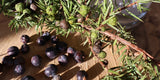 Ein Wacholderzweig und Wacholderbeeren liegen auf einer Holzscheibe.