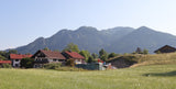 Bayerische Häuser im Dorf Lenggries, dahinter Bergpanorama. Symbolbild für die Oberlandbrennerei.