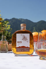 Eine Flasche WUYD Single Malt Whisky Batch 2 auf einem gedeckten Tisch mit Bergpanorama.