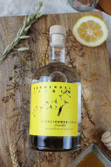 Flower Power Gin Lemon Flasche liegt auf Brett zwischen Botanicals